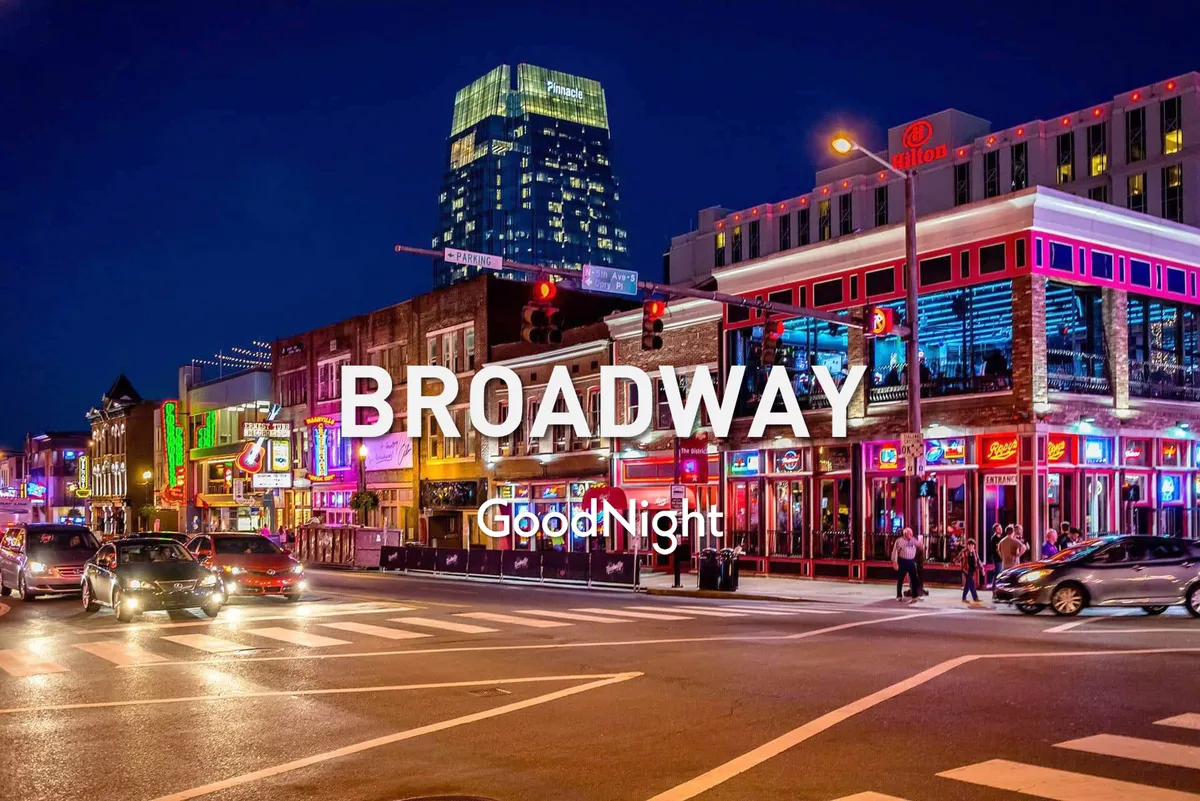 A lively nighttime street scene in Nashville’s West End Corridor, with neon signs, bustling sidewalks, traffic, and illuminated buildings. The image evokes the energetic vibe of local nightlife, music venues, and dining options in close proximity to the apartment.